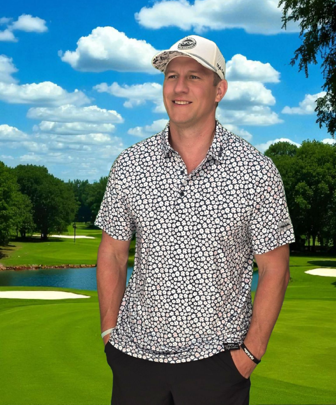 Man standing on a golf course with a floral golf polo and cap, blue sky with clouds in the background