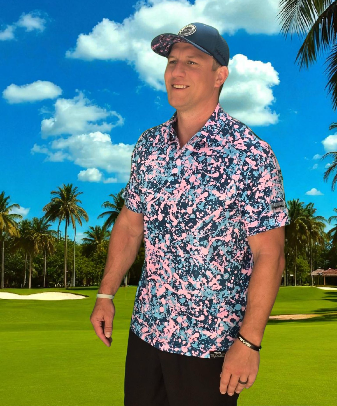 Man wearing a colorful golf polo shirt and cap on a golf course with palm trees in the background