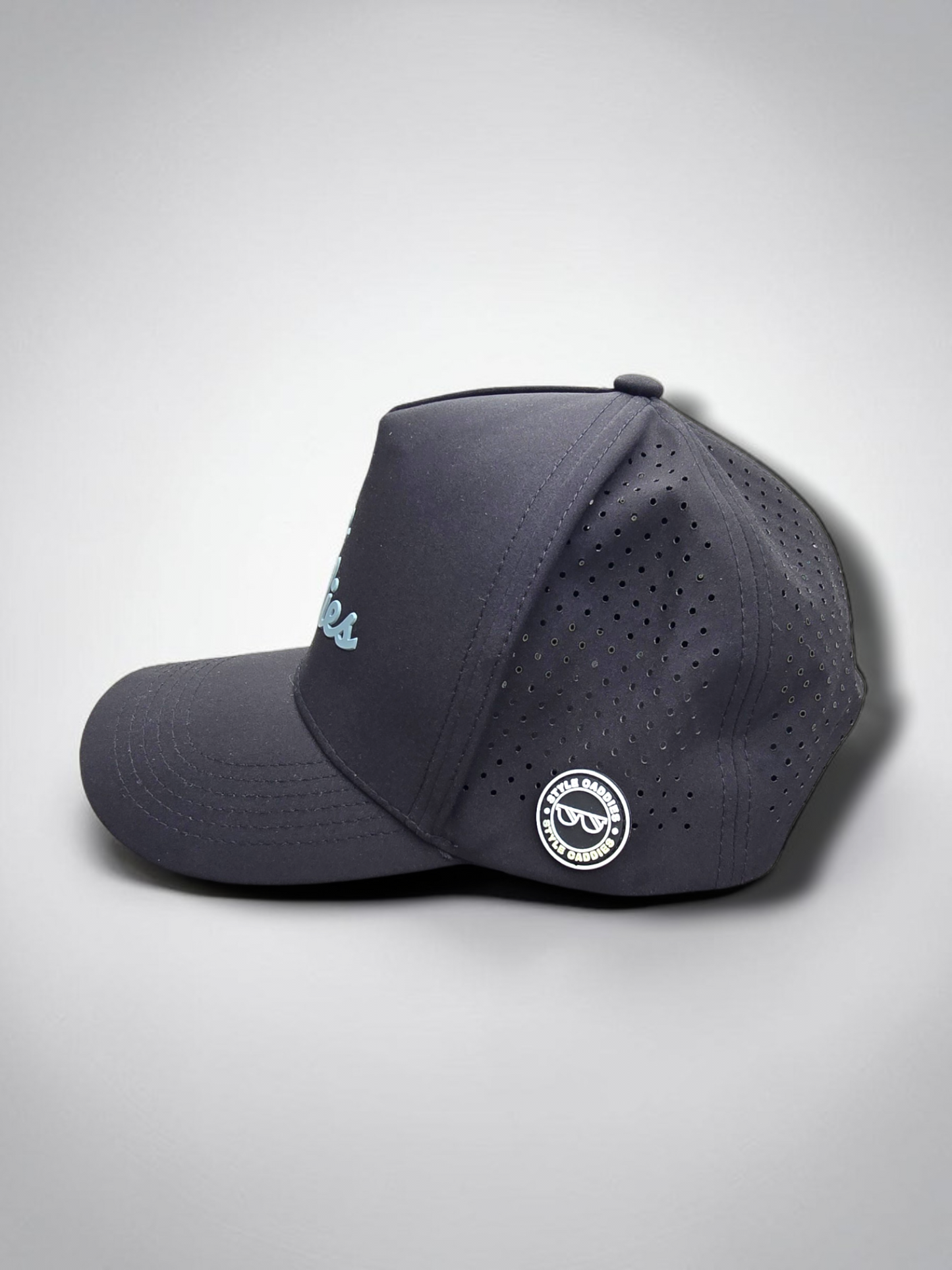 Black Style Caddies hat side profile close-up showing the perforated panel and circular logo patch